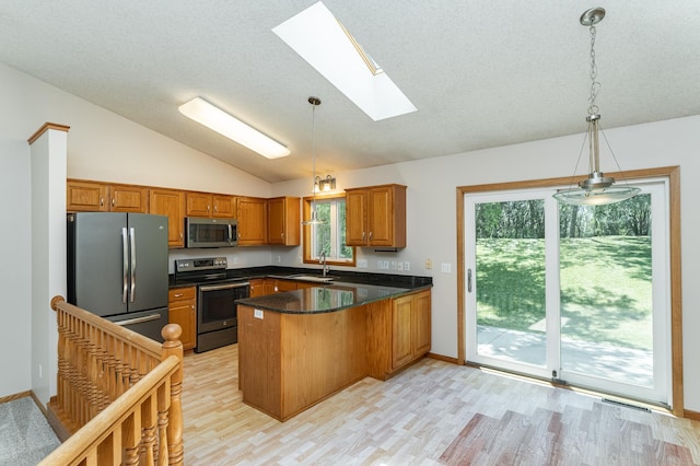 816 Bristol Ln NE, Rochester, MN 55906 - kitchen with appliances with stainless steel finishes, a peninsula, vaulted ceiling, brown cabinets, and a skylight
