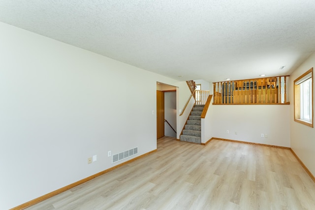 816 Bristol Ln NE, Rochester, MN 55906 - unfurnished living room with wood finished floors, stairs, and a textured ceiling