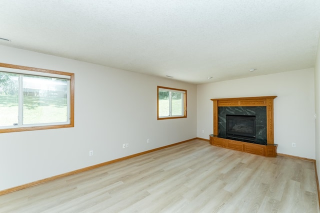 816 Bristol Ln NE, Rochester, MN 55906 - unfurnished living room featuring light wood-style flooring, a high end fireplace, and a textured ceiling