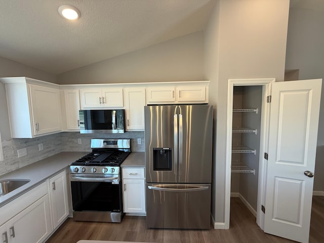 2883 Ivory Ave NE, Saint Michael, MN 55376 - kitchen featuring stainless steel appliances, vaulted ceiling, dark wood finished floors, white cabinetry, and backsplash
