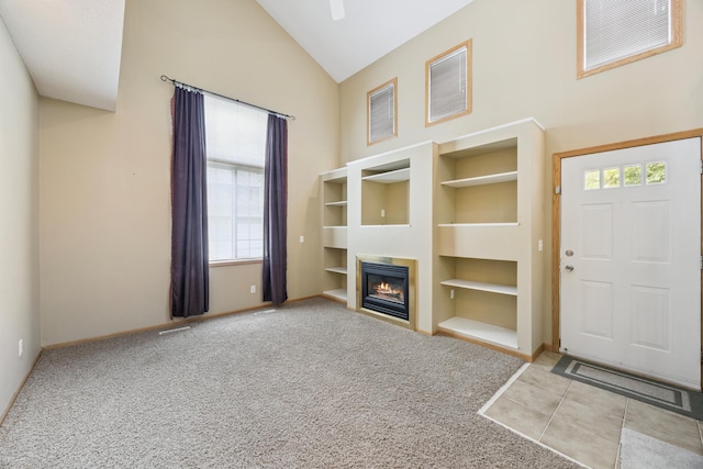 14000 Erwin Ct, Eden Prairie, MN 55344 - unfurnished living room featuring built in features, high vaulted ceiling, a glass covered fireplace, and carpet flooring