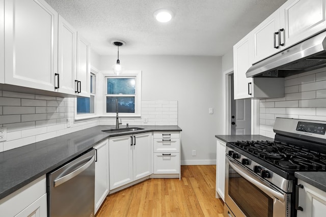 188 Cleveland Ave S, Saint Paul, MN 55105 - kitchen featuring appliances with stainless steel finishes, under cabinet range hood, backsplash, dark countertops, and white cabinetry