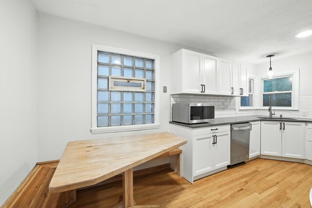 188 Cleveland Ave S, Saint Paul, MN 55105 - kitchen featuring appliances with stainless steel finishes, backsplash, light wood finished floors, dark countertops, and white cabinetry