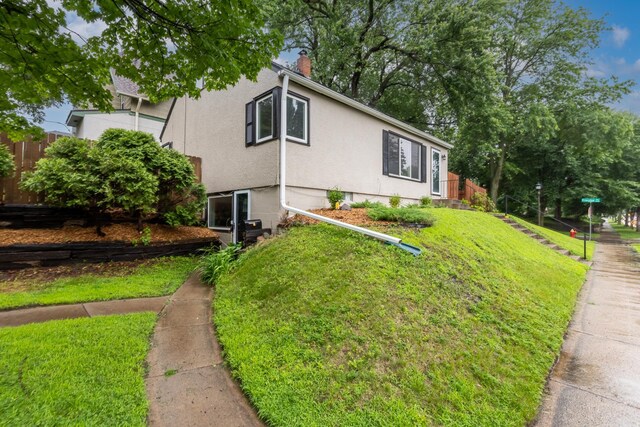 188 Cleveland Ave S, Saint Paul, MN 55105 - view of home's exterior with stucco siding, a yard, and a chimney