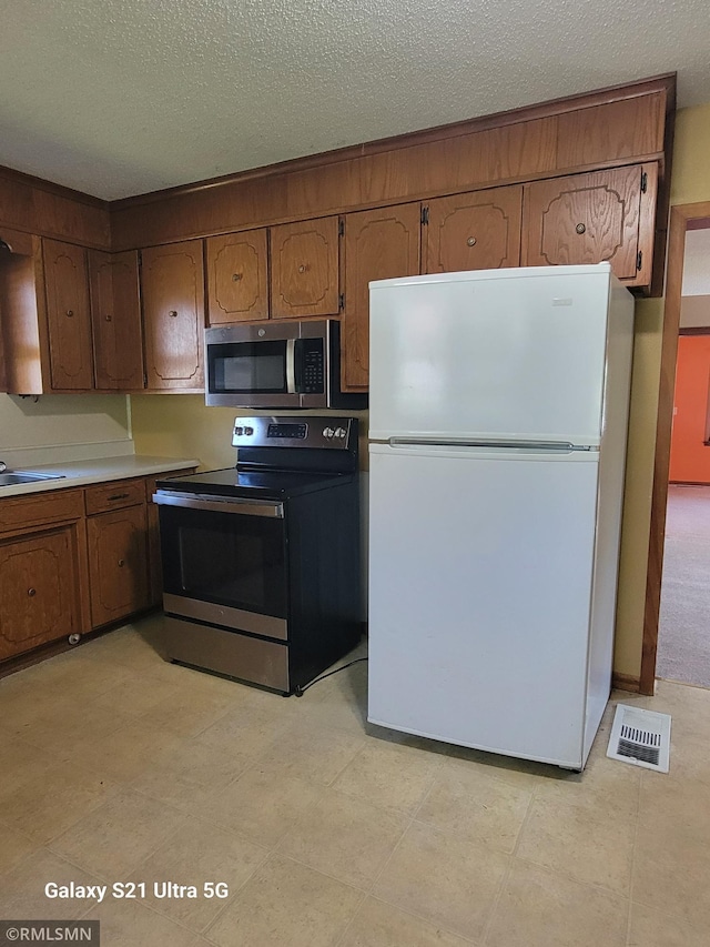 150 Gillis Ave S, Browerville, MN 56438 - kitchen with appliances with stainless steel finishes, a textured ceiling, brown cabinetry, and light countertops