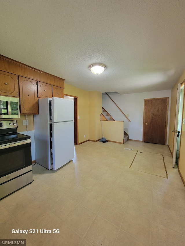 150 Gillis Ave S, Browerville, MN 56438 - kitchen featuring stainless steel appliances, a textured ceiling, and brown cabinets