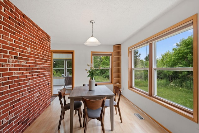 20170 Oxboro Ln N, Scandia, MN 55047 - dining space featuring a textured ceiling, light wood finished floors, brick wall, and built in shelves