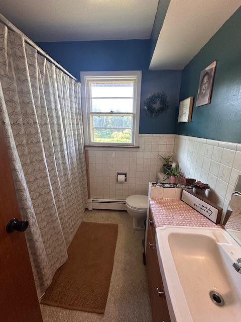 3507 Salo Rd, Waasa Twp, MN 55732 - full bath featuring a baseboard radiator, tile walls, vanity, wainscoting, and a shower with curtain