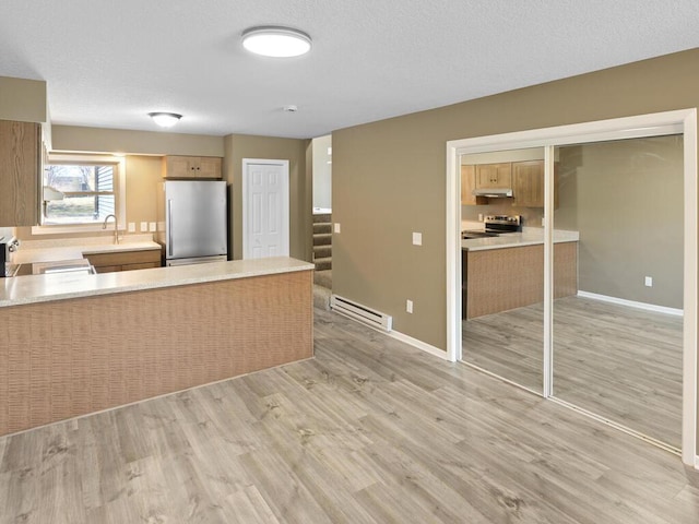 26161 8th St W, Zimmerman, MN 55398 - kitchen with stainless steel appliances, a baseboard heating unit, under cabinet range hood, light wood-style floors, and light countertops