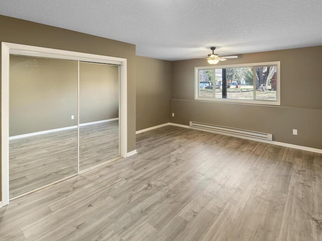 26161 8th St W, Zimmerman, MN 55398 - unfurnished bedroom with a baseboard radiator, a textured ceiling, wood finished floors, a closet, and a ceiling fan
