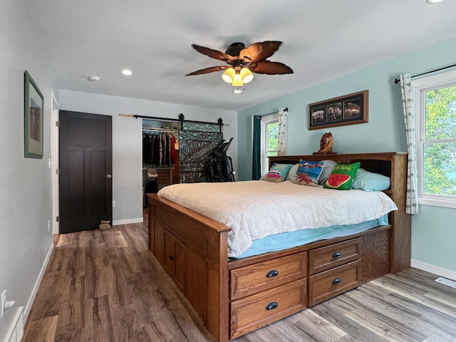 34 Shady Rest Rd, Lake Sarah Twp, MN 56132 - bedroom with wood finished floors, a barn door, ceiling fan, and recessed lighting