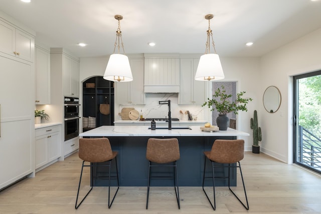 625 Ivy Falls Ave, Mendota Heights, MN 55118 - kitchen featuring double oven, light wood finished floors, a kitchen island with sink, a breakfast bar, and backsplash