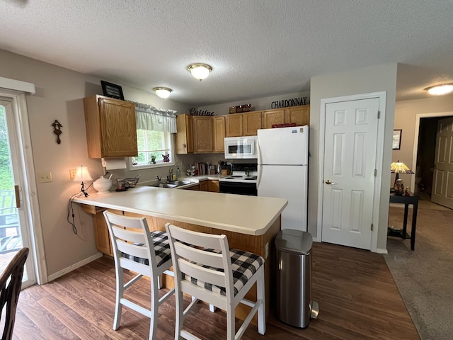15965 Red Sand Cir, Brainerd, MN 56401 - kitchen featuring white appliances, a peninsula, a textured ceiling, light countertops, and a kitchen breakfast bar
