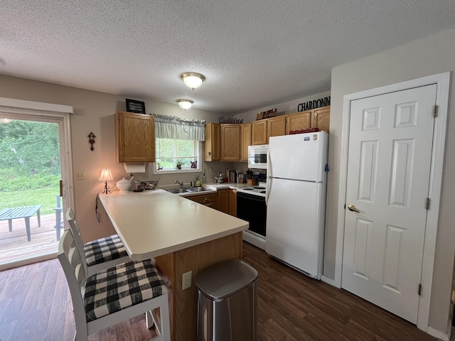 15965 Red Sand Cir, Brainerd, MN 56401 - kitchen with white appliances, a peninsula, a breakfast bar area, light countertops, and dark wood-type flooring