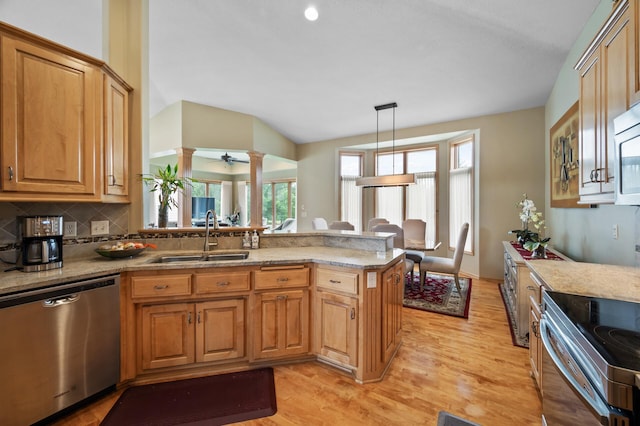 11880 Dunkirk Cir NE, Blaine, MN 55449 - kitchen featuring stainless steel appliances, a peninsula, light wood-type flooring, decorative backsplash, and decorative columns