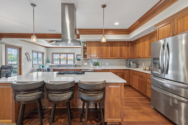 7471 260th St, Wyoming, MN 55092 - kitchen featuring stainless steel appliances, island exhaust hood, brown cabinets, light countertops, and crown molding