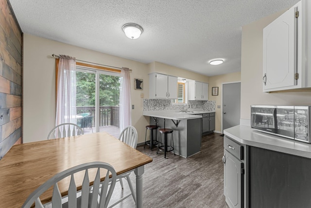 6071 Red Fox Run, North Branch, MN 55056 - kitchen featuring a peninsula, wood finished floors, light countertops, white cabinets, and a kitchen bar