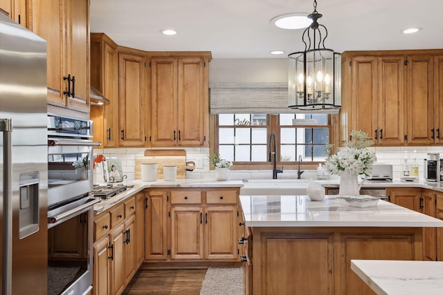 9525 Shore Trl N, Forest Lake, MN 55025 - kitchen with appliances with stainless steel finishes, tasteful backsplash, recessed lighting, a chandelier, and brown cabinetry