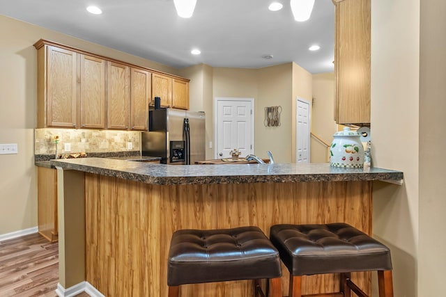15618 Emerald Dr N Unit 2, Hugo, MN 55038 - kitchen with stainless steel refrigerator with ice dispenser, a peninsula, dark countertops, backsplash, and light wood-style flooring