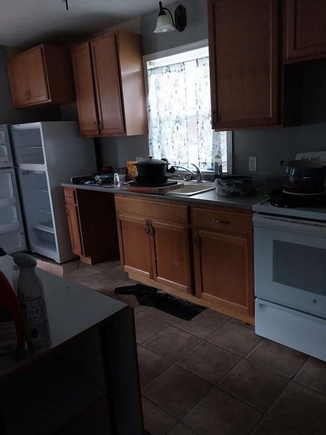 206 20th St S, Benson, MN 56215 - kitchen with electric stove, dark countertops, freestanding refrigerator, and brown cabinets