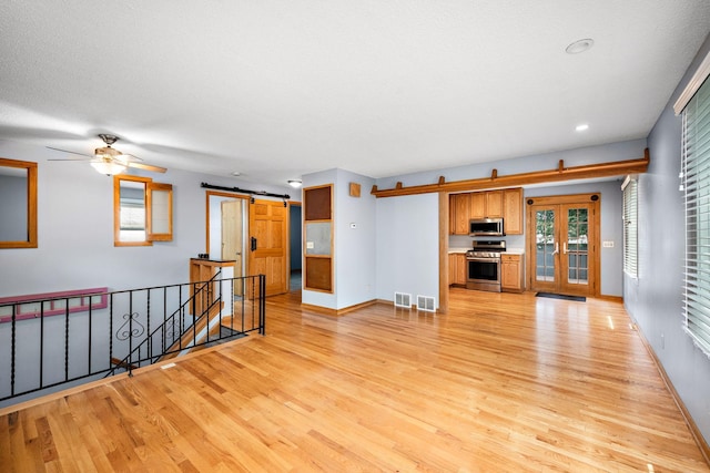711 Quincy St NE, Minneapolis, MN 55413 - unfurnished living room with a barn door, light wood-style floors, a ceiling fan, recessed lighting, and plenty of natural light