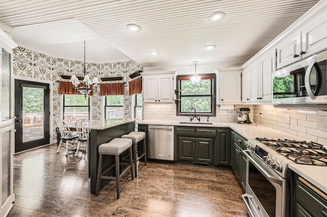 791 139th Ln NW, Andover, MN 55304 - kitchen featuring appliances with stainless steel finishes, white cabinets, light countertops, dark wood-type flooring, and decorative backsplash