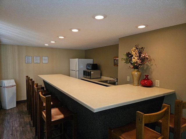 1855 Silver Bell Rd Unit 301, Eagan, MN 55122 - kitchen featuring stainless steel microwave, freestanding refrigerator, dark wood-style floors, a peninsula, and a kitchen breakfast bar