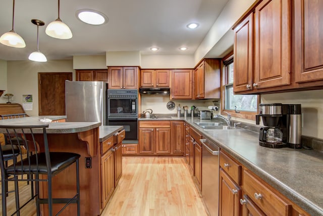 715 River Heights Rd SW, Menomonie, WI 54751 - kitchen with black appliances, a kitchen breakfast bar, light wood-style floors, brown cabinets, and decorative light fixtures
