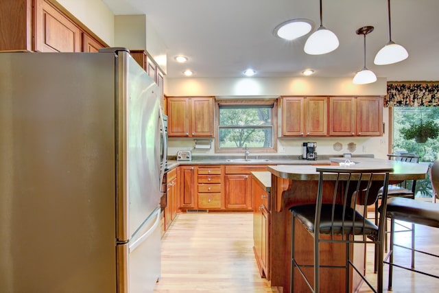 715 River Heights Rd SW, Menomonie, WI 54751 - kitchen with freestanding refrigerator, a breakfast bar area, light wood-type flooring, a kitchen island, and pendant lighting