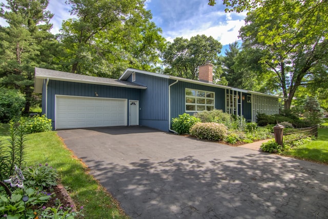 715 River Heights Rd SW, Menomonie, WI 54751 - mid-century modern home featuring a chimney, an attached garage, and driveway