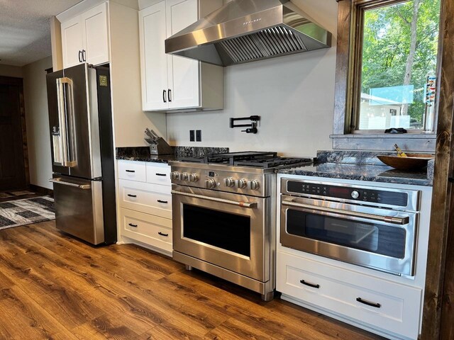 8766 Interlachen Rd, Lake Shore, MN 56468 - kitchen featuring premium appliances, wall chimney exhaust hood, dark wood-style floors, white cabinetry, and dark stone countertops