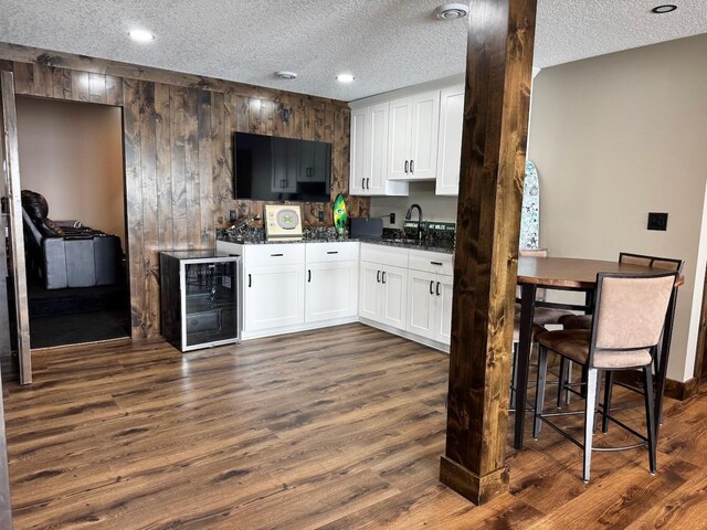 8766 Interlachen Rd, Lake Shore, MN 56468 - kitchen featuring beverage cooler, dark wood-type flooring, white cabinets, a textured ceiling, and wood walls