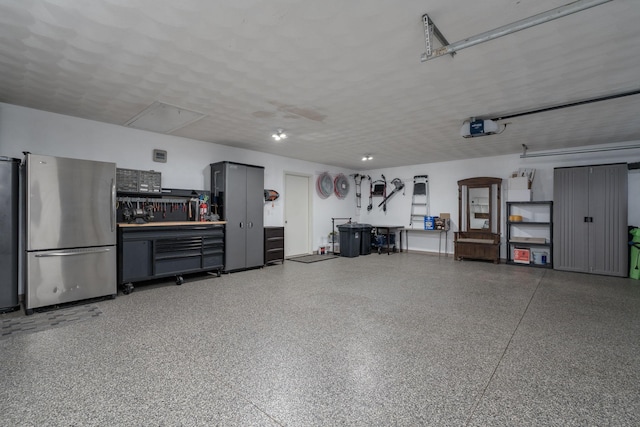 102 Terrace Vw E, Decoria Twp, MN 56001 - garage featuring freestanding refrigerator, a garage door opener, refrigerator, and a workshop area