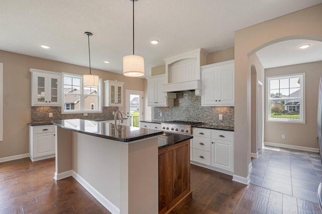 6430 Bluestem Cir, Corcoran, MN 55340 - kitchen with arched walkways, backsplash, gas stovetop, glass insert cabinets, and recessed lighting
