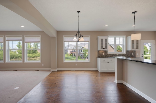 6430 Bluestem Cir, Corcoran, MN 55340 - kitchen with dark countertops, glass insert cabinets, white cabinetry, dark wood-style floors, and decorative light fixtures
