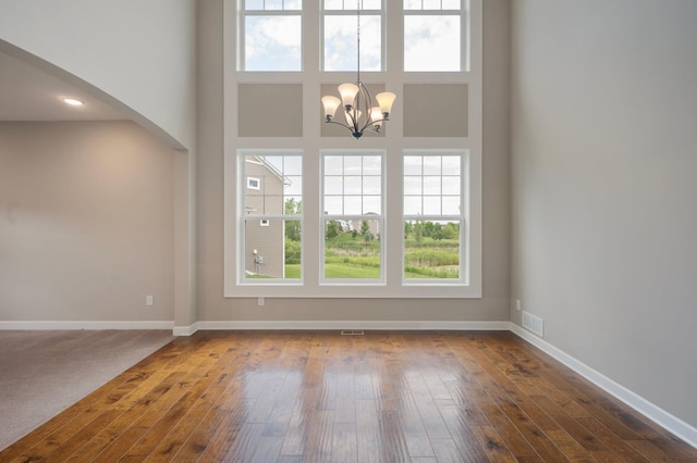 6430 Bluestem Cir, Corcoran, MN 55340 - unfurnished living room featuring a chandelier, dark wood-style floors, arched walkways, and a towering ceiling