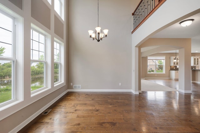 6430 Bluestem Cir, Corcoran, MN 55340 - spare room featuring a chandelier, hardwood / wood-style floors, arched walkways, and a high ceiling