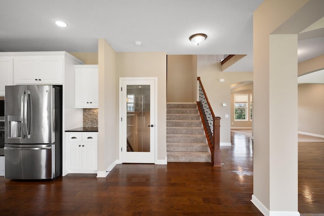 6430 Bluestem Cir, Corcoran, MN 55340 - kitchen featuring stainless steel fridge with ice dispenser, arched walkways, dark wood-style flooring, tasteful backsplash, and white cabinets