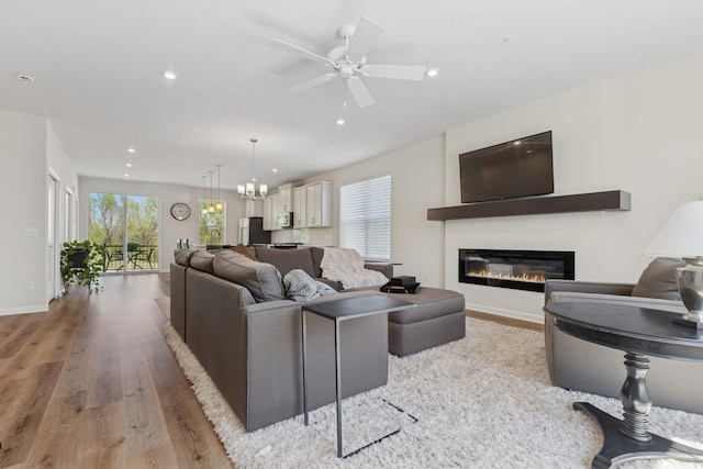 6645 Jody Ave S, Cottage Grove, MN 55016 - living area featuring light wood-style flooring, a glass covered fireplace, recessed lighting, a chandelier, and a ceiling fan