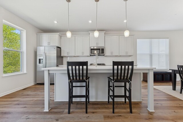 6645 Jody Ave S, Cottage Grove, MN 55016 - kitchen with appliances with stainless steel finishes, a center island with sink, light countertops, a breakfast bar area, and recessed lighting