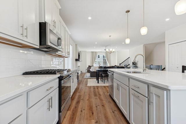 6645 Jody Ave S, Cottage Grove, MN 55016 - kitchen with appliances with stainless steel finishes, a chandelier, decorative backsplash, light wood-style floors, and light countertops