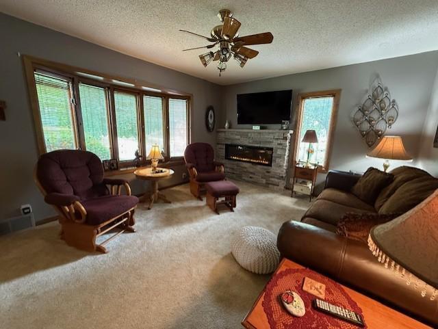 688 Miller Ave, Windom, MN 56101 - carpeted living area with healthy amount of natural light, ceiling fan, a glass covered fireplace, and a textured ceiling