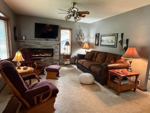 688 Miller Ave, Windom, MN 56101 - living room with a fireplace, ceiling fan, a textured ceiling, and carpet flooring