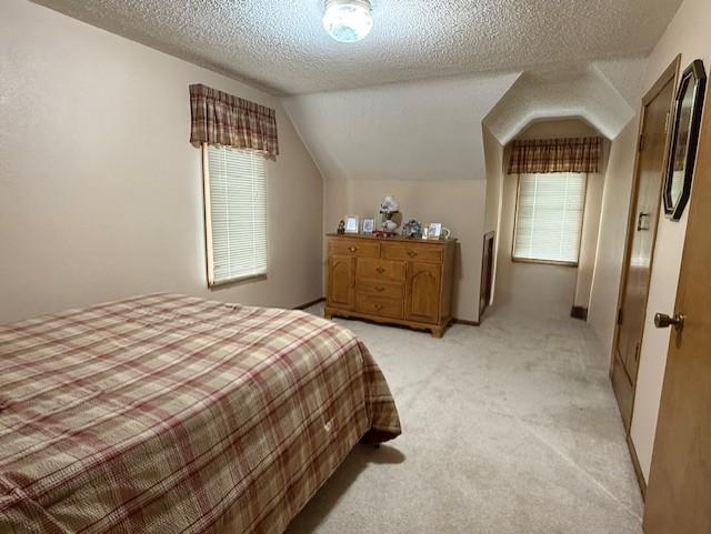 688 Miller Ave, Windom, MN 56101 - bedroom featuring light carpet, a textured ceiling, and vaulted ceiling