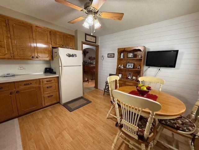 688 Miller Ave, Windom, MN 56101 - kitchen featuring freestanding refrigerator, light wood-style flooring, brown cabinets, and wooden walls