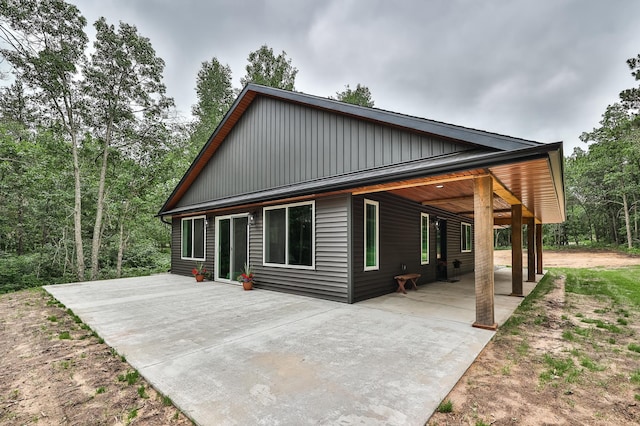 19566 Early Bird Dr, Park Rapids, MN 56470 - view of front of home with a patio area, concrete driveway, an attached carport, and board and batten siding