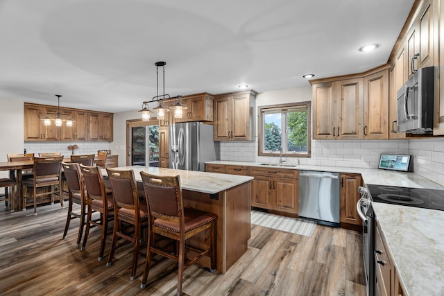 876 162nd St, Hammond, WI 54015 - kitchen featuring appliances with stainless steel finishes, decorative backsplash, a breakfast bar area, wood finished floors, and brown cabinets