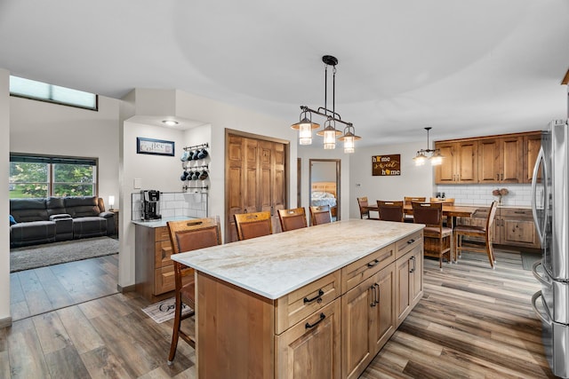 876 162nd St, Hammond, WI 54015 - kitchen with freestanding refrigerator, wood finished floors, a kitchen island, backsplash, and a kitchen breakfast bar