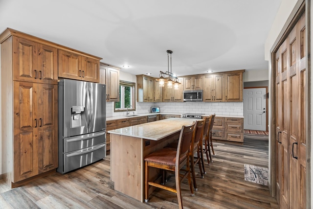 876 162nd St, Hammond, WI 54015 - kitchen with appliances with stainless steel finishes, backsplash, dark wood-style flooring, a breakfast bar, and a center island
