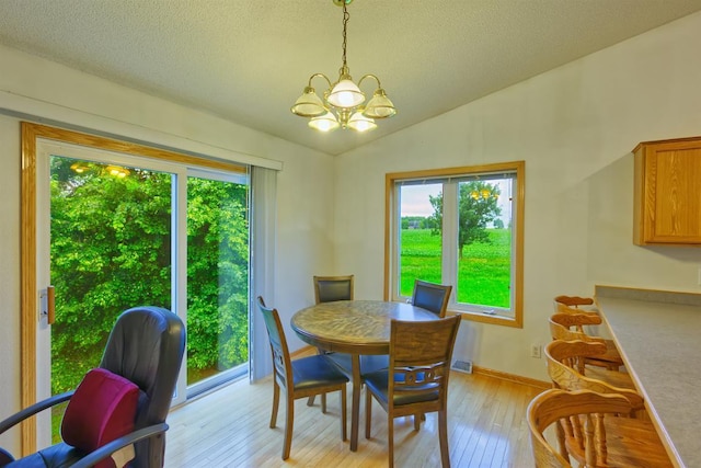 343 Perch Ln, Winsted, MN 55395 - dining space with plenty of natural light, a chandelier, light wood-style floors, lofted ceiling, and a textured ceiling